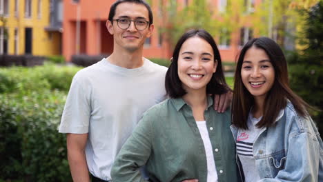 Group-Of-Three-Young-Japanese-Friends-Smiling-And-Looking-At-Camera-While-Standing-Outdoors-1