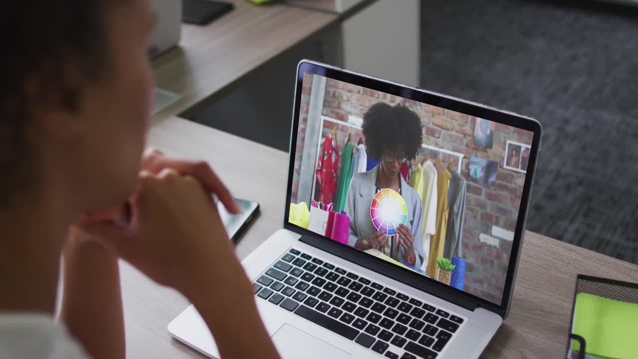 mujer afroamericana haciendo una videollamada en una computadora portátil con una colega en la oficina