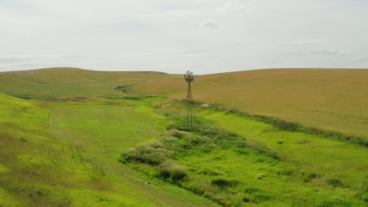 목장의 개울 옆에 있는 작은 계곡에 홀로 서 있는 오래된 에어모터 풍차 펌프
