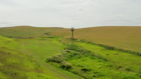 Old-Aermotor-windmill-pump-standing-alone-in-small-valley-beside-creek-on-ranch