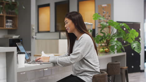 businesswoman working on laptop in kitchen area of modern office