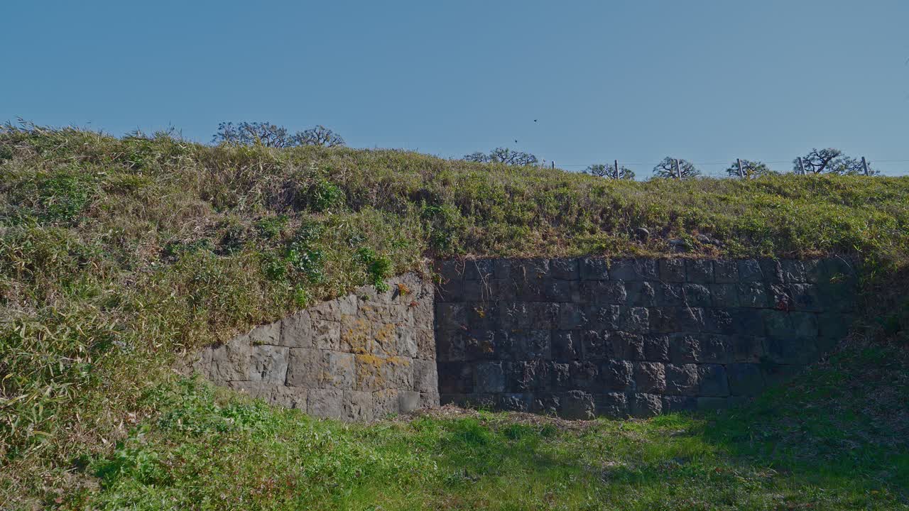 Una vista del pesante muro di contenimento in pietra che sostiene il terrapieno della fortezza. Queste mura erano essenziali per l'integrità strutturale delle fortificazioni di difesa costiera durante il periodo Edo