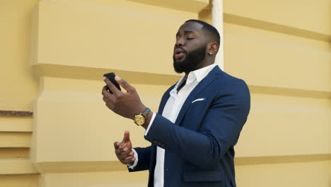 Serious-afro-man-having-video-call.-African-businessman-talking-phone-outdoors.