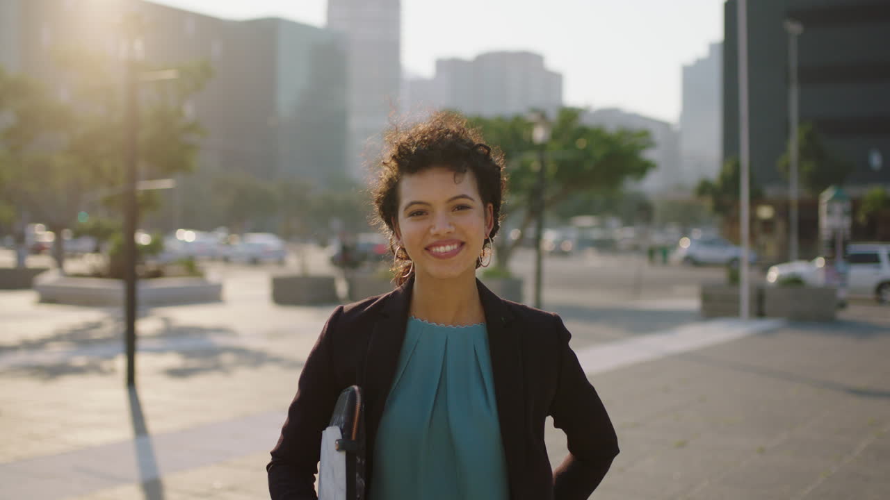 retrato de elegante jovem mulher de negócios hispânica rindo feliz no fundo de uma cidade urbana ventosa estagiária estudante bem sucedida
