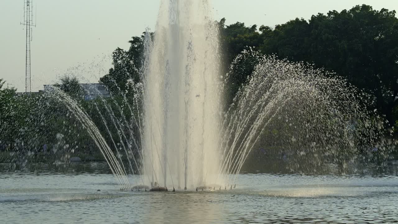 Une magnifique fontaine urbaine présente des jets d'eau dynamiques sur fond de soirée sereine.