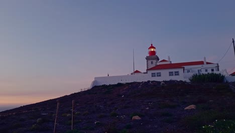 sun rising in the distance, lighthouse sends it’s warning beam across the sea