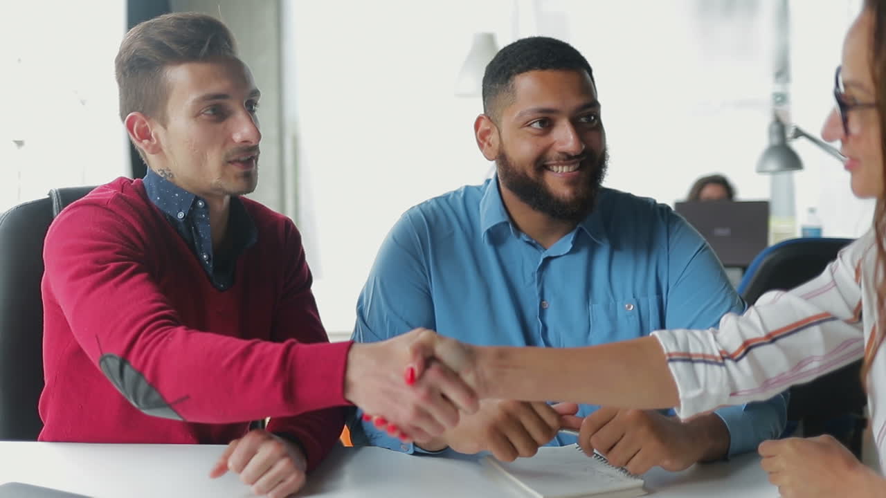 Handsome bearded man shaking hands with beautiful woman.