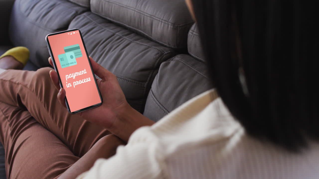 Biracial woman on couch using smartphone for online shopping, slow motion