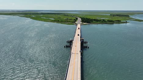 cars on bridge between marshland and islands during sunny day in wildwood, new jersey. aerial wide shot. blue sky in summer. idyllic landscape in america