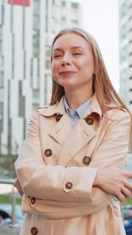 feliz mujer de negocios madura usando un teléfono inteligente y mirando a la cámara mientras está de pie en la calle del centro