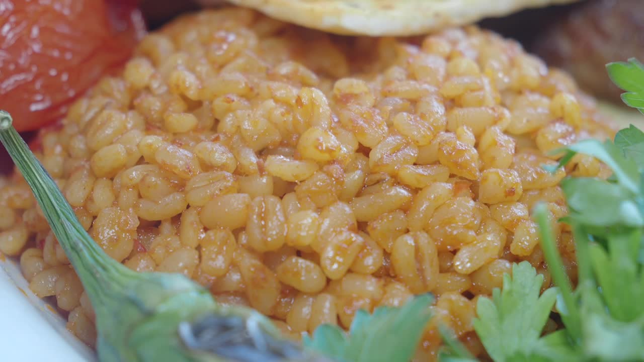 Close up of bulgur pilaf with tomato, parsley, and bread
