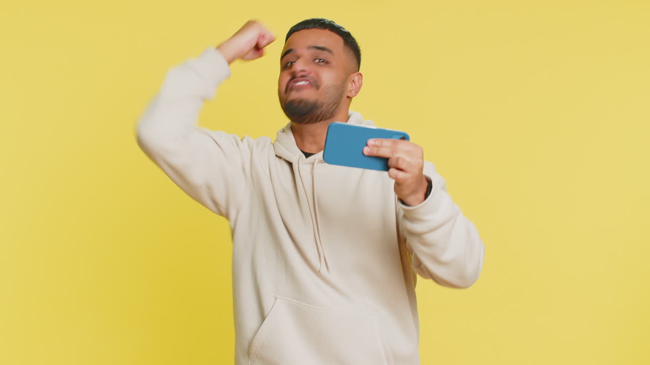 Happy man playing racing drive simulator shooter video games on smartphone celebrate victory win