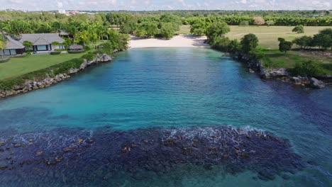 playa caleton, hidden tropical paradise in la romana, dominican republic, crystal-clear turquoise waters, white sandy beach, lush greenery, and coastal villas. aerial backward