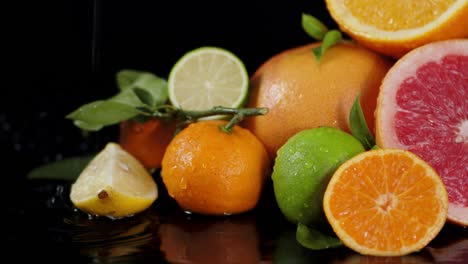 different kinds of ripe citrus under water drops.