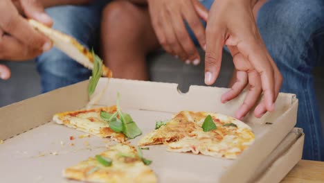 diversos amigos adolescentes comiendo pizza y sentados en el sofá, cámara lenta