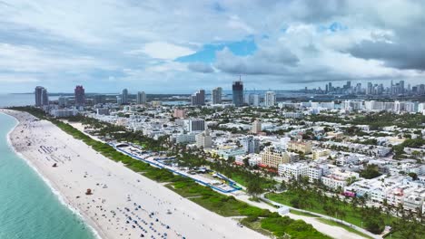 Espectaculares-Imágenes-Aéreas-De-Drones-De-Una-Playa-De-Arena-En-Miami,-EE.-UU.,-Tomas-De-Un-Pedestal-Ascendente-Lento-Que-Capturan-Un-Paisaje-Marino-Fascinante,-Con-Gente-Relajándose-Y-Edificios-Altos.