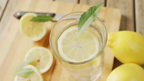 video of glass with lemonade and lemons on wooden board and wooden surface