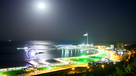 ferris wheel on the background of the sea and the lunar path. traffic on the roads. time lapse