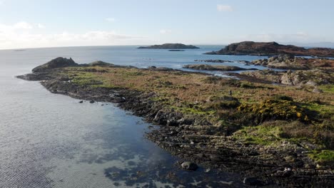 AERIAL---Rocky-beaches-and-shallow-water-on-the-Isle-of-Gigha,-Kintyre,-Scotland