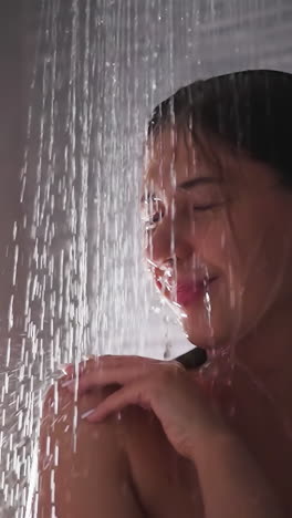 cheerful woman washes in shower sprays closeup. happy young lady enjoys hygienic routine in home bathroom. body cleansing procedures in washroom