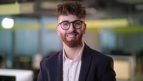 portrait of cheerful male boss in suit with beard looking to camera and smiling. good looking caucasian man team leader in modern company office