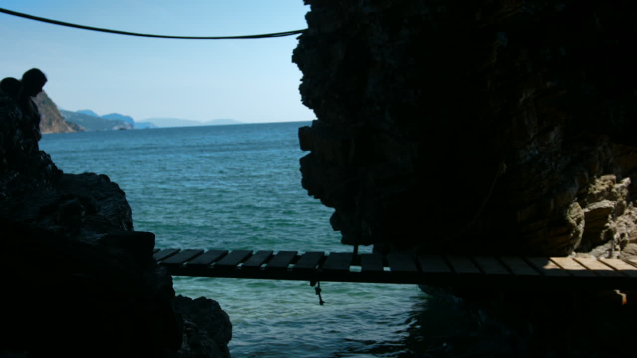 바다 를 바라보는 물 위 의 나무 다리 를 고 있는 사람