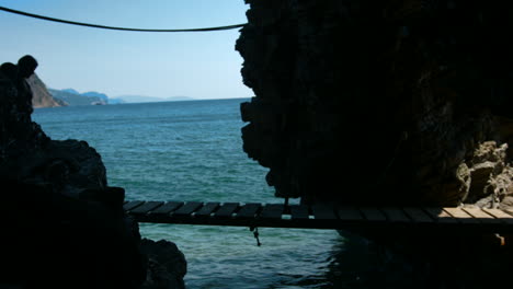 persona caminando sobre un puente de madera sobre el agua con una vista al mar