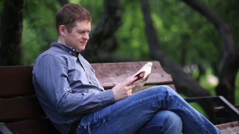 man reads newspaper on bench in the park 2