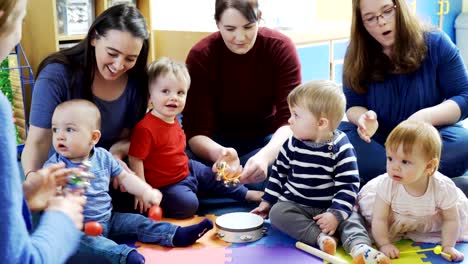 mothers and babies playing instruments and singing at music group