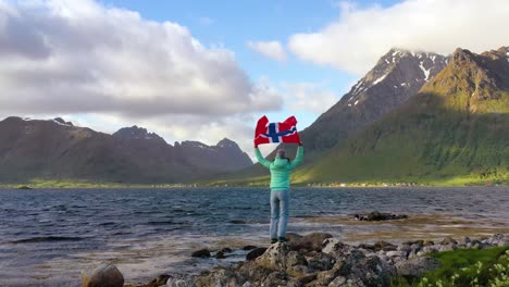 mujer con una bandera de noruega ondeando en el fondo de la naturaleza