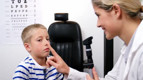 female optometrist examining young patient with ophthalmoscope