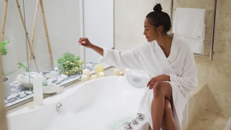 mixed race woman sitting by a bathtub at home