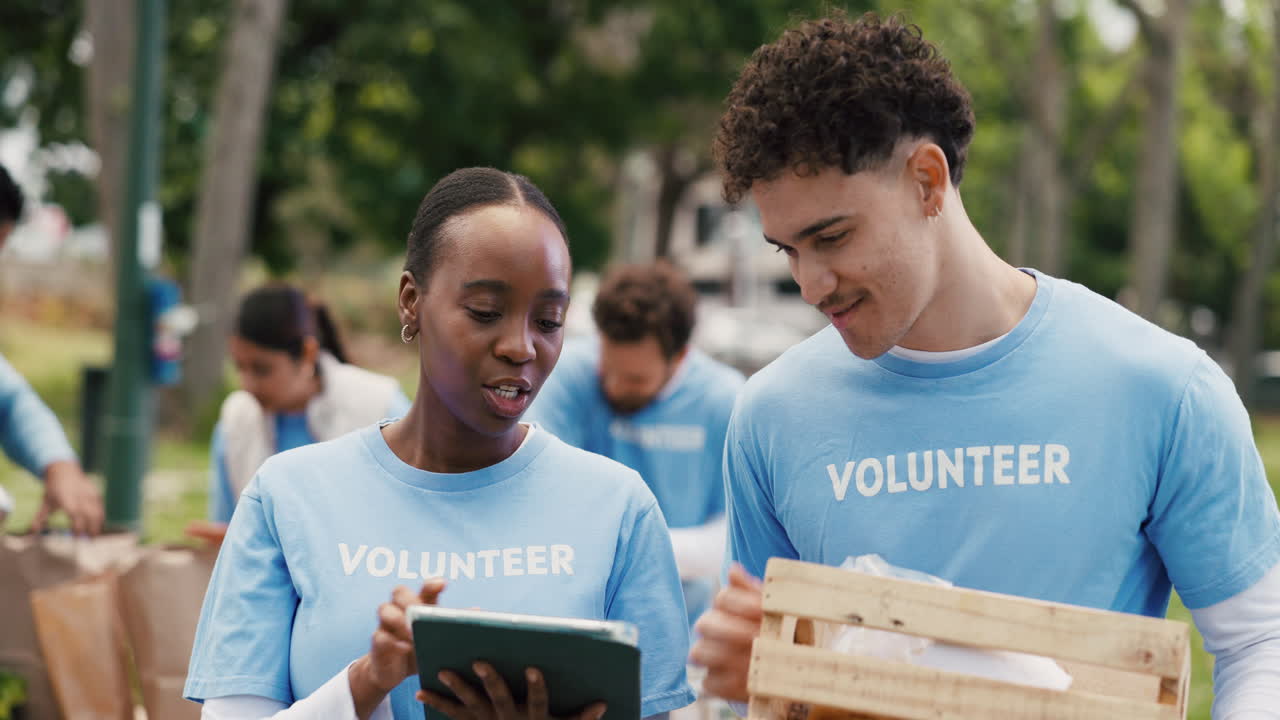 Diverse Volunteers Discussing Plans on a Tablet in a Park