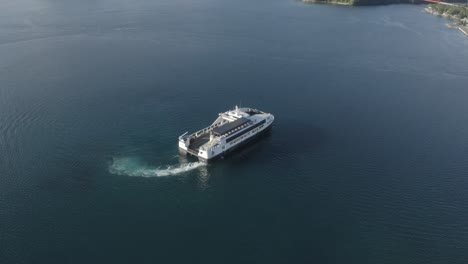 a ferry boat cruising in slow motion over the calm blue sea, leaving the port in the philippines on a sunny day - aerial drone shot, orbiting shot