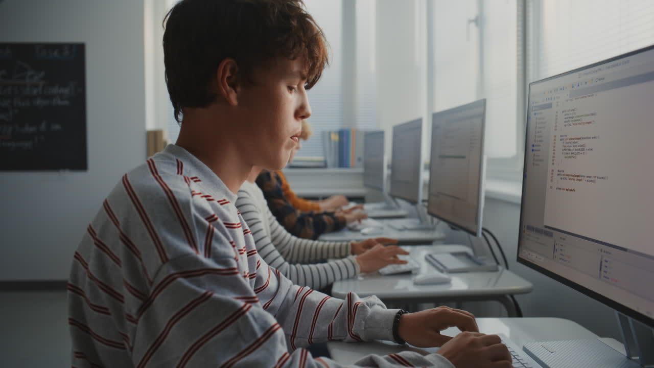 Male Student Learning Programming at Computer in Bright Classroom