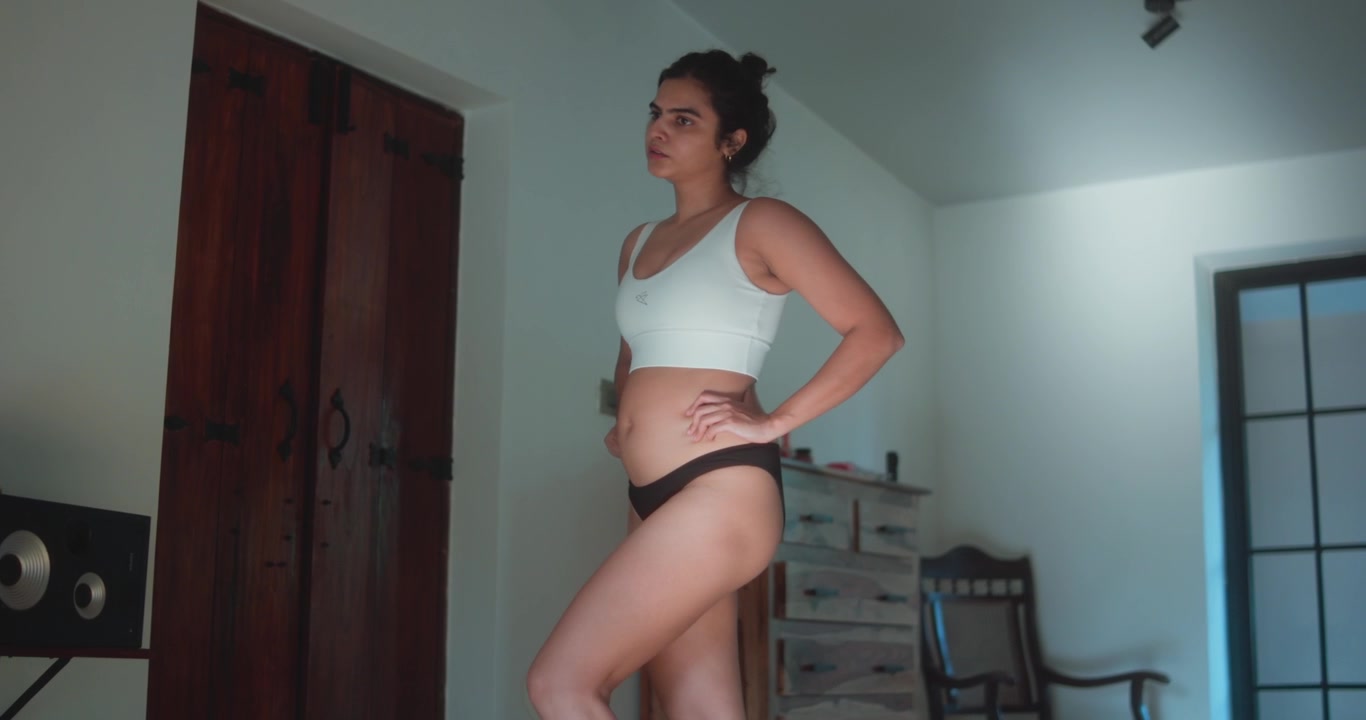 Woman practicing standing hip mobility and leg movement exercises indoors. Functional fitness routine focused on flexibility, balance, body control, and lower-body strength.