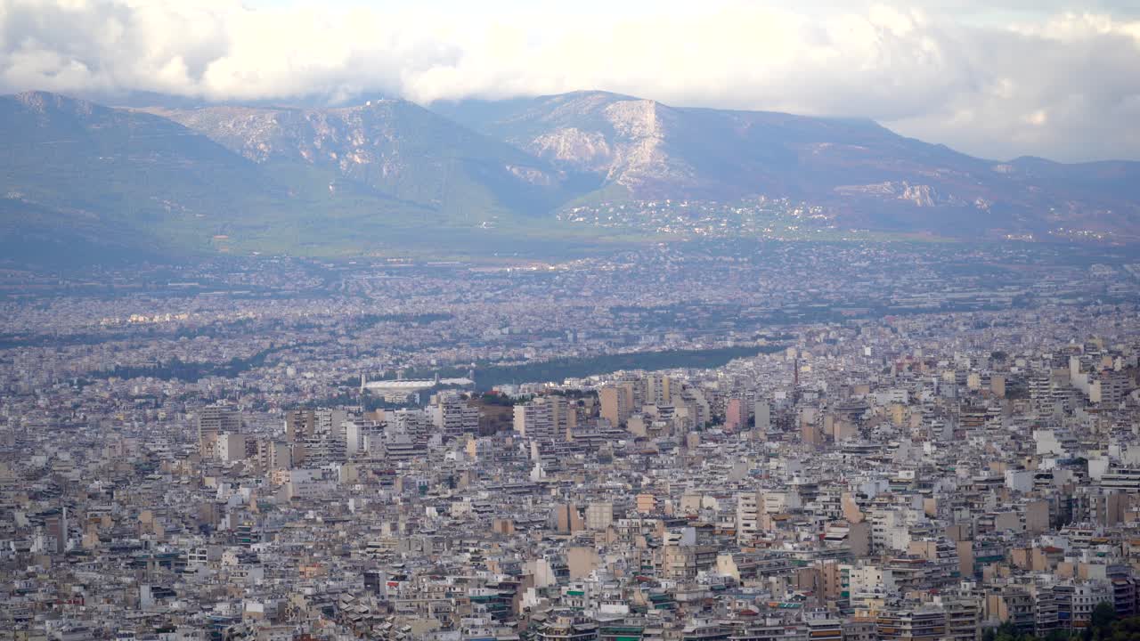 panorama interminable del paisaje urbano, edificios de la ciudad de atenas con nubes pesadas en las montañas