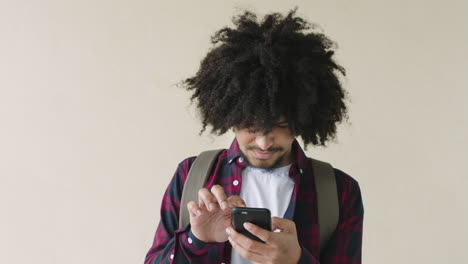 portrait of young mixed race man with afro using phone social media texting