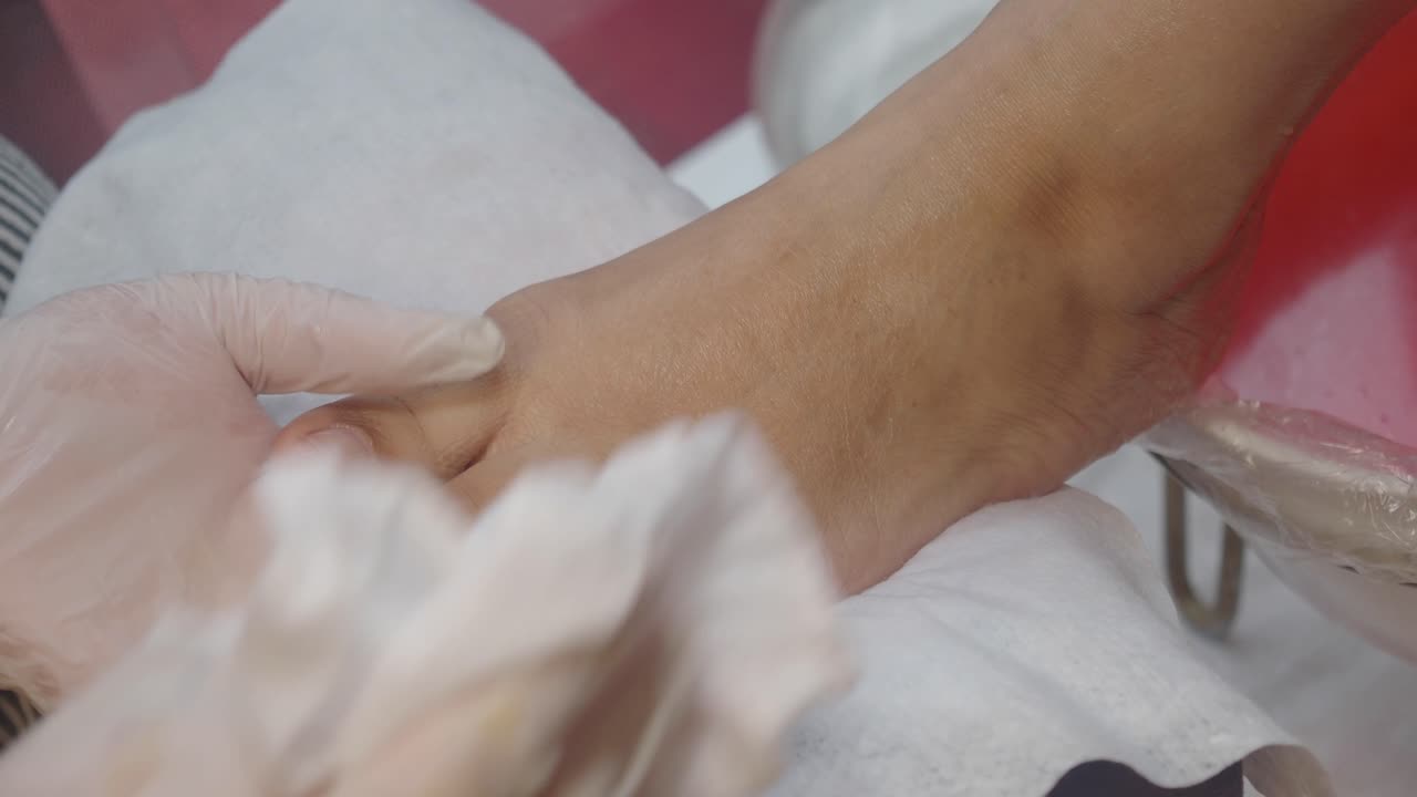 Pedicurist Wiping Woman's Foot with a Towel in a Salon