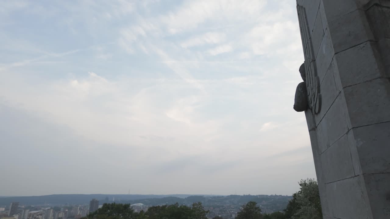 Tall stone monument honoring the 14th Line Regiment in Liege, Belgium, under cloudy skies