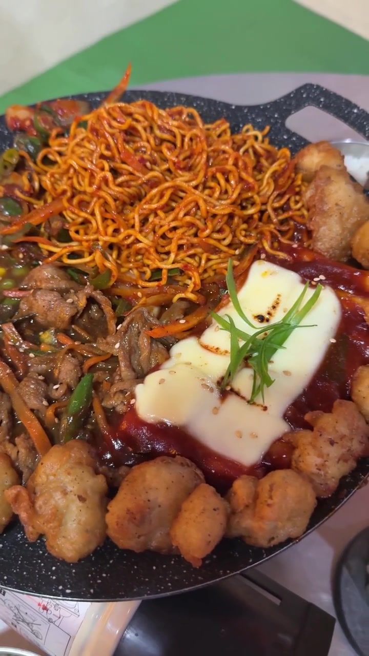 Piring Mendesis Berisi Mi Pedas, Daging Tumis, Sayuran, dan Keju Leleh