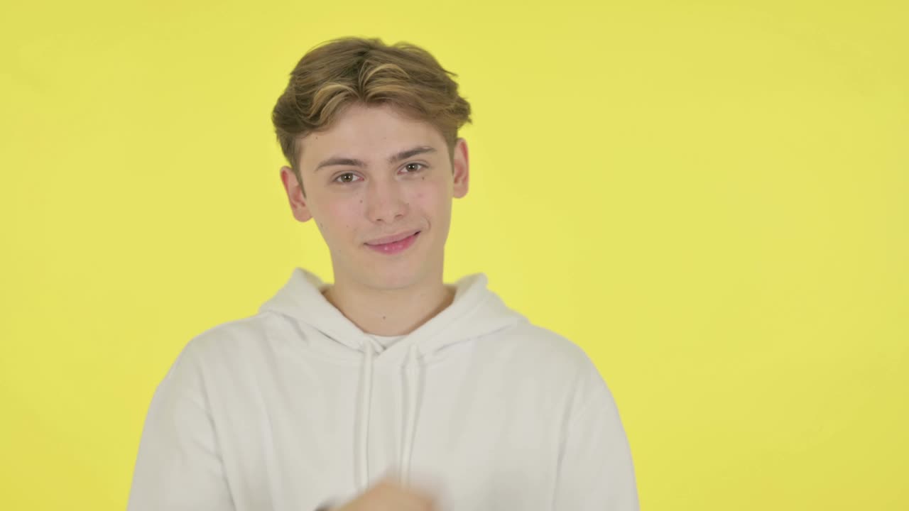 노란색 배경 에 있는 제품 을 가리키는 젊은 남자