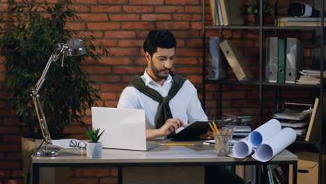 young arabian businessman checking and reading some documents or contract while sitting in the office at the computer