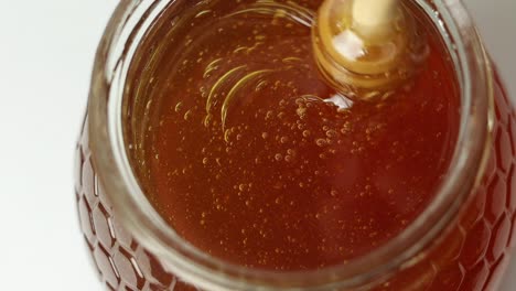 person stirring honey with dipper