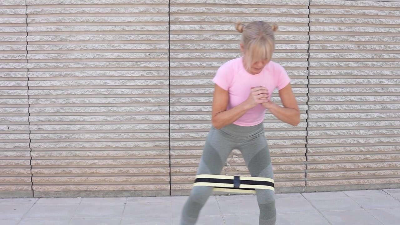 A woman is doing resistance band side steps to target her lower body muscles during a workout