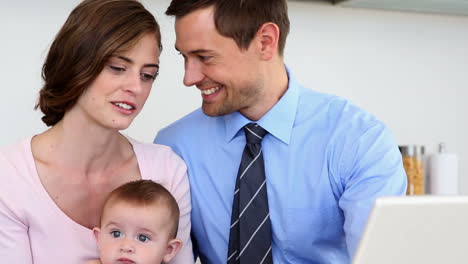 Happy-parents-using-laptop-with-their-baby-son-in-the-morning