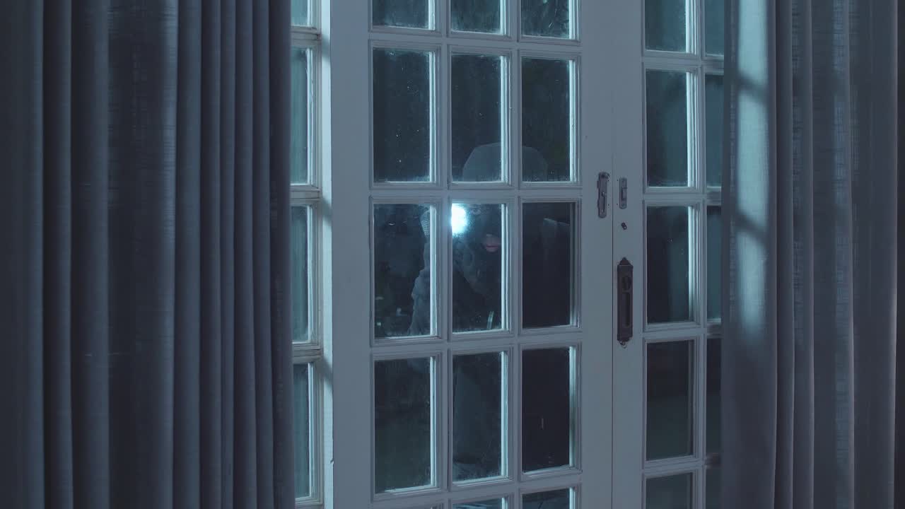 침입자가 밤에 유리 문을 통해 쳐다보고 있습니다.