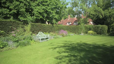 Panning-shot-around-a-secret-garden-with-a-green-wooden-bench-amongst-the-slower-bed