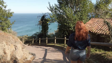 woman walking on a path towards the ocean