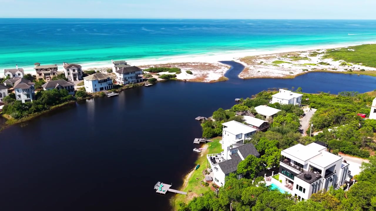 Dronekuvaa Stallworth-järven yllä, jota ympäröivät ylelliset kiinteistöt ja turkoosi lahti, Santa Rosa Beach, Florida, USA.